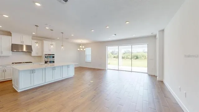 a view of a kitchen with kitchen island a sink wooden floor and a large window