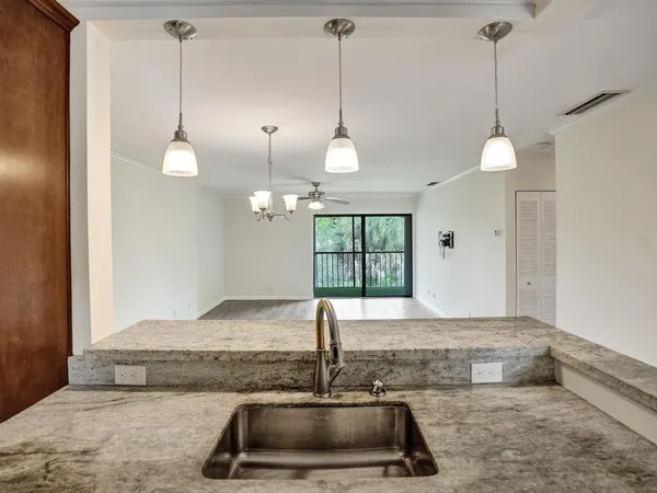 a kitchen with a sink a faucet a chandelier and living room view