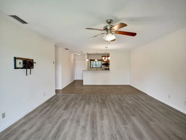 a view of empty room with wooden floor and fan