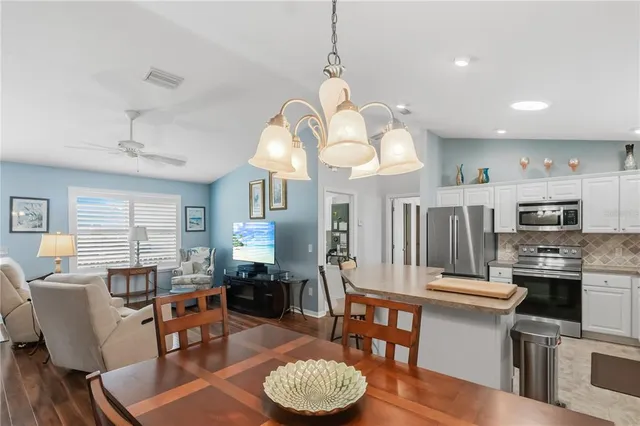 a living room with stainless steel appliances kitchen island a dining table and chairs