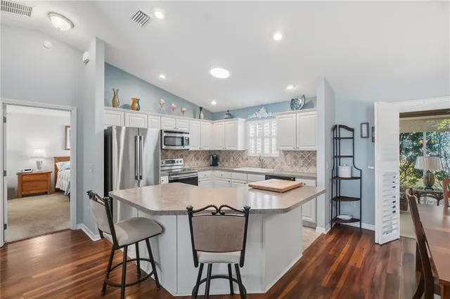 a large kitchen with kitchen island a large counter top space and stainless steel appliances