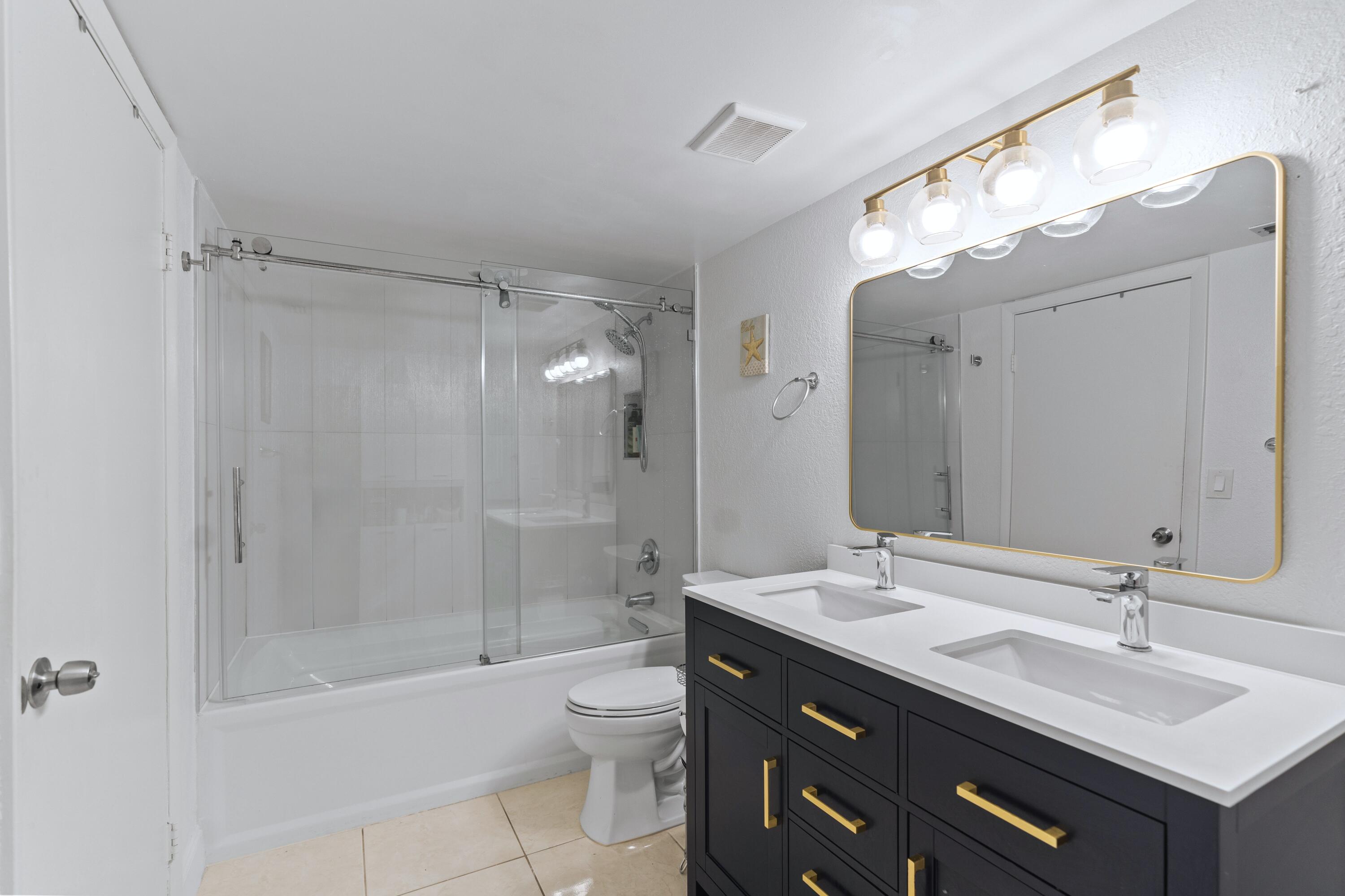 9927 Boca Gardens Trail, Unit A Boca Raton, FL 33496 - Photo 12 of 63 a bathroom with a double vanity sink mirror double shower and a bathtub