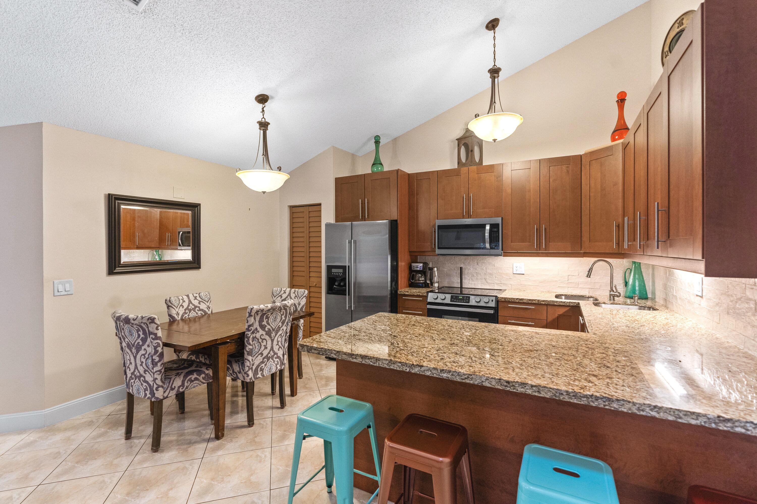 9927 Boca Gardens Trail, Unit A Boca Raton, FL 33496 - Photo 18 of 63 a kitchen with granite countertop a stove a sink a dining table and chairs with wooden floor