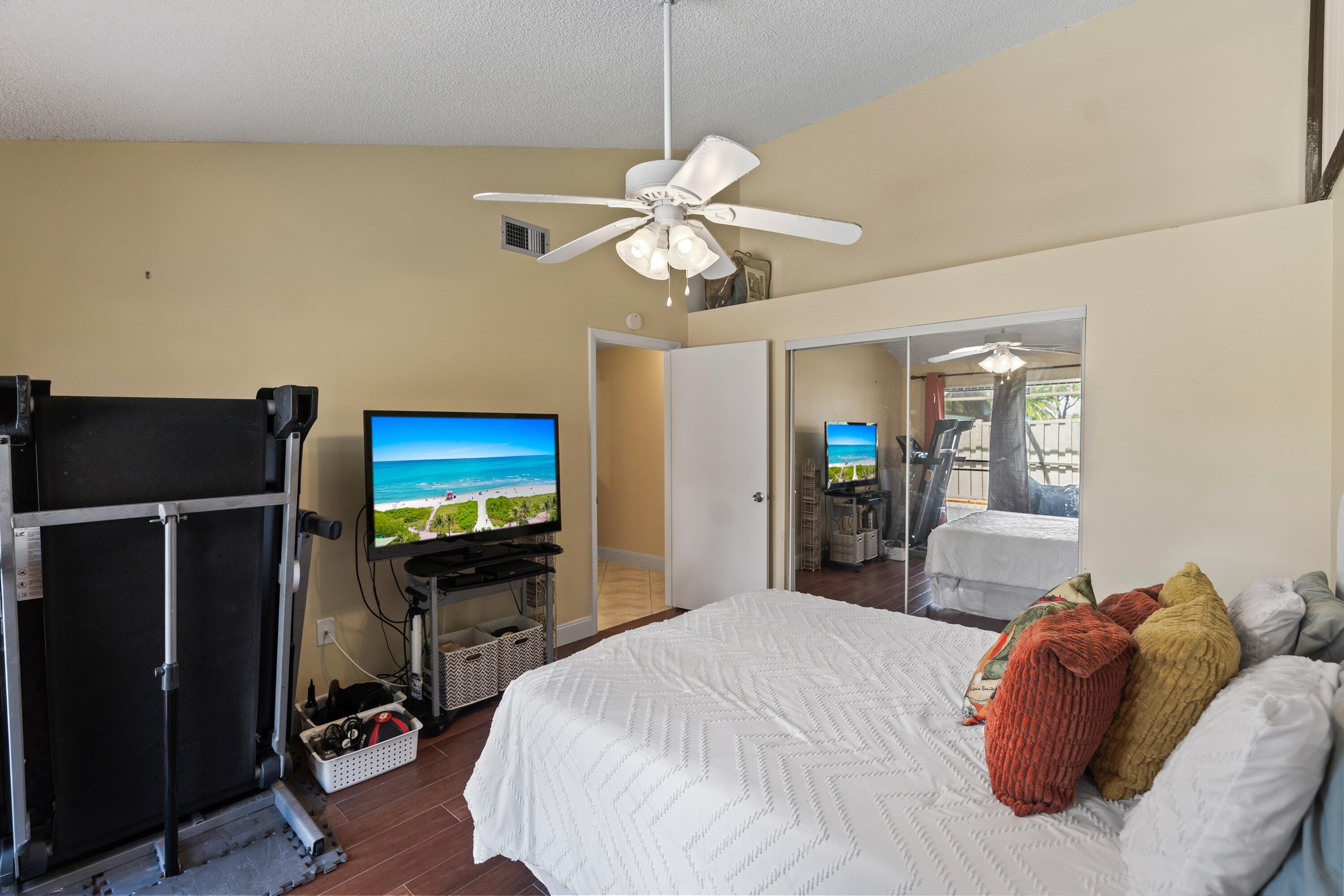 9927 Boca Gardens Trail, Unit A Boca Raton, FL 33496 - Photo 45 of 63 a bedroom with a bed and a flat tv screen on dresser