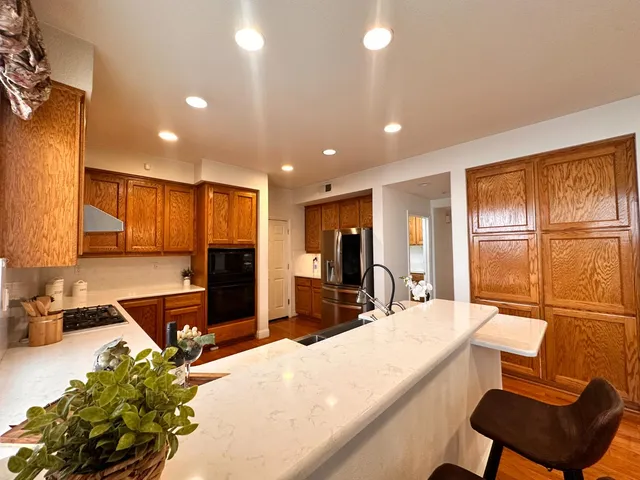 a view of kitchen with granite countertop refrigerator dining table and chairs