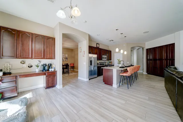 a kitchen with stainless steel appliances kitchen island granite countertop a table chairs and a refrigerator