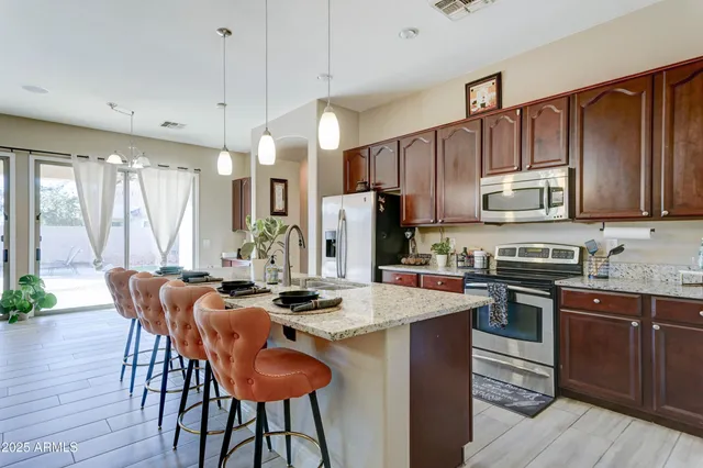 a kitchen with stainless steel appliances granite countertop a stove a refrigerator a sink dishwasher a dining table and chairs with wooden floor