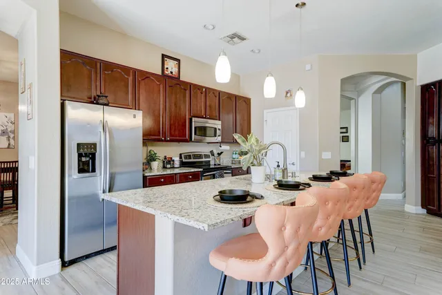 a kitchen with stainless steel appliances granite countertop a dining table and chairs