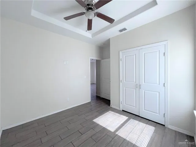 an empty room with ceiling fan and windows