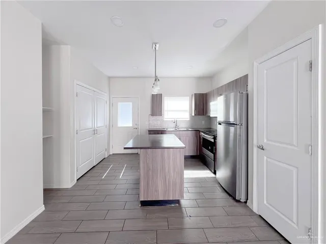 a kitchen with kitchen island white cabinets and refrigerator