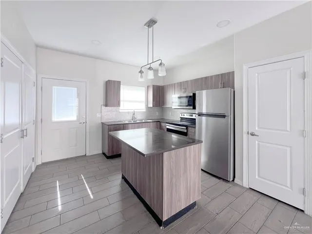 a kitchen with kitchen island granite countertop cabinets and refrigerator