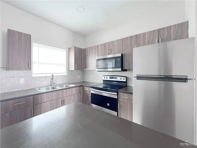 a kitchen with granite countertop a refrigerator stove and sink