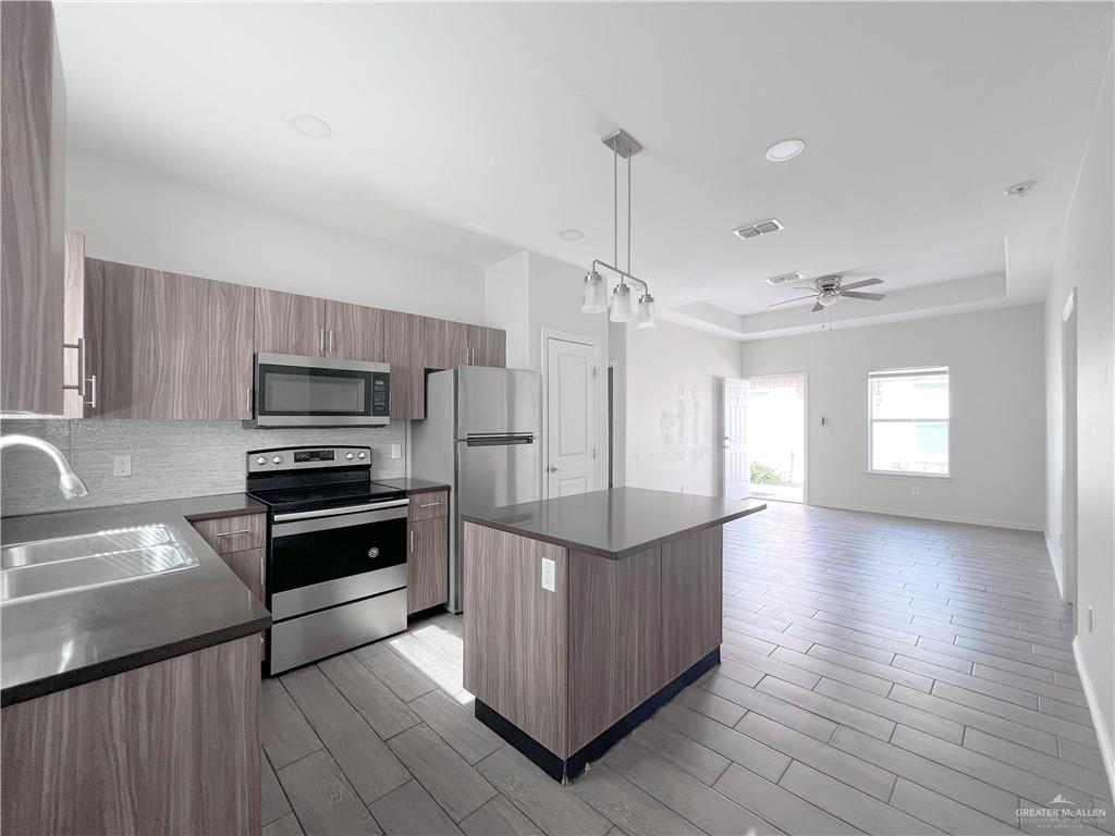 1609 West Cortlandt Street, Unit 3 Edinburg, TX 78541 - Photo 9 of 21 a kitchen with stainless steel appliances kitchen island granite countertop a stove a refrigerator and a sink with wooden floor