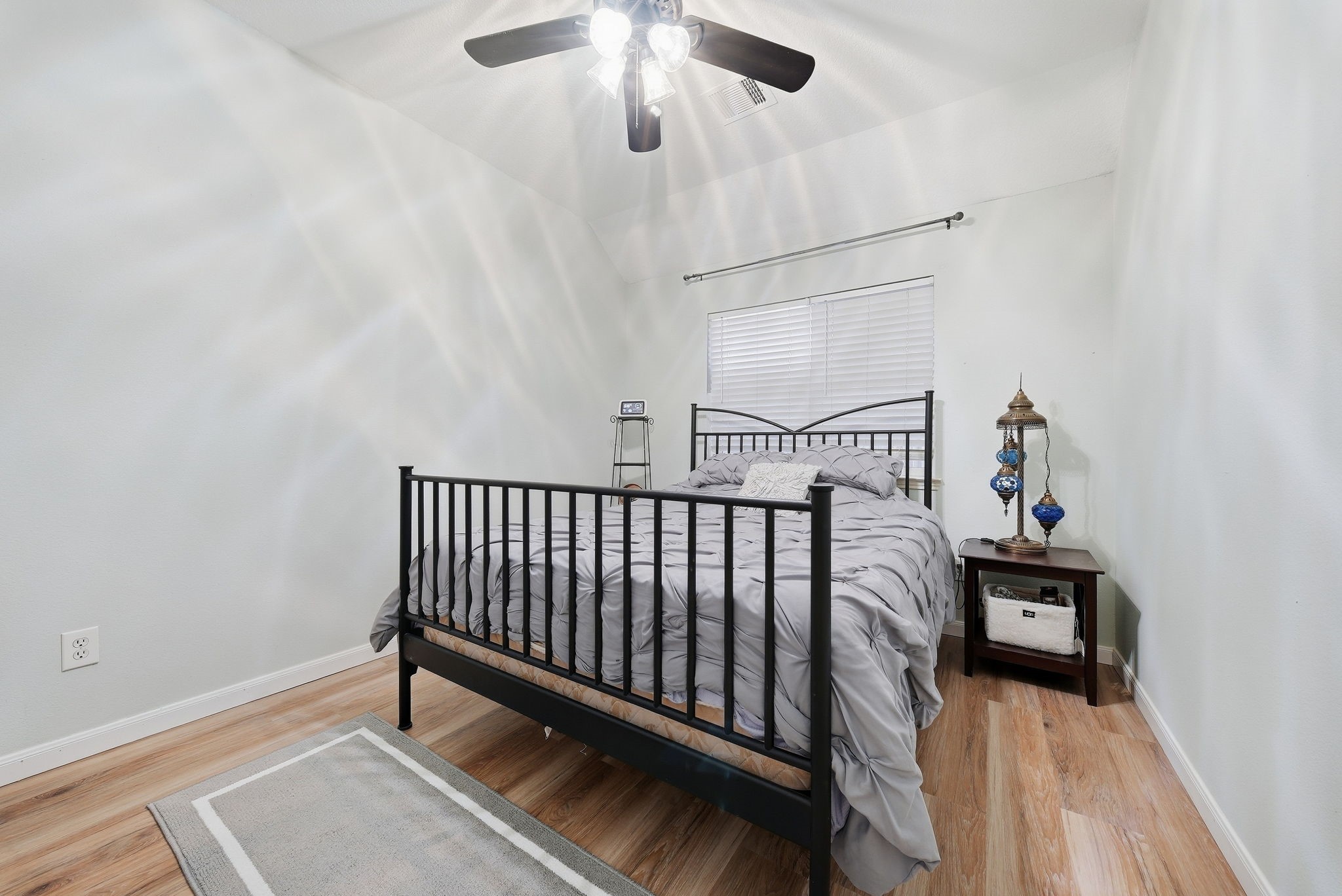 2223 Lazy Trail Path Court Spring, TX 77373 - Photo 16 of 23 Cozy bedroom featuring a sleek metal bed frame, soft gray bedding, and stylish hardwood flooring, complemented by a ceiling fan for added comfort.