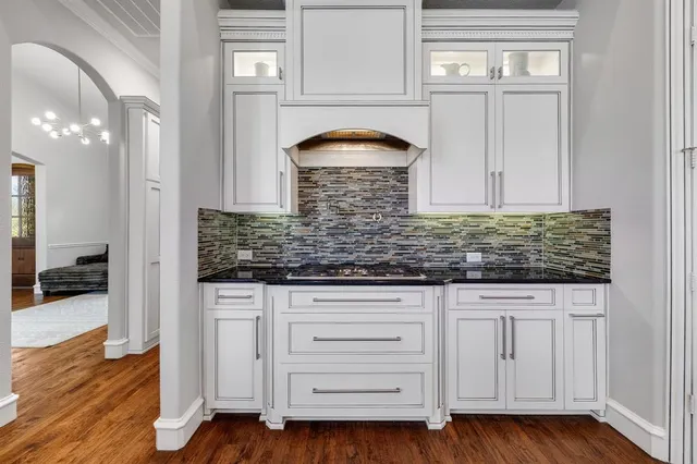 a kitchen with granite countertop white cabinets and a wooden floor