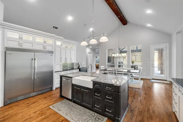 a kitchen with stainless steel appliances granite countertop a sink a stove and a wooden floors