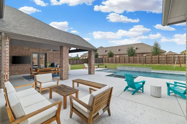 a view of a patio with a dining table and chairs with swimming pool