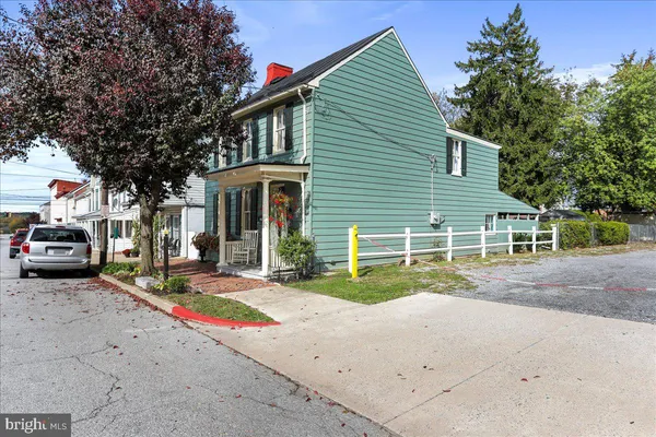 a view of a house with a small yard and a large tree