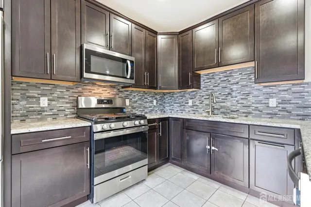 a kitchen with stainless steel appliances granite countertop a sink stove and microwave