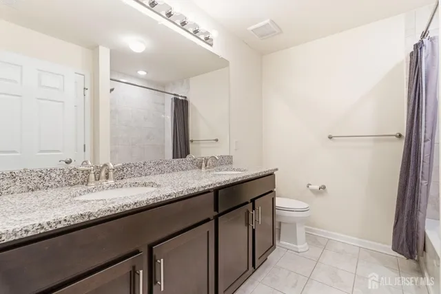 a bathroom with a granite countertop sink a toilet and a mirror