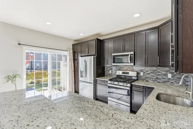 a kitchen with granite countertop a refrigerator and a sink