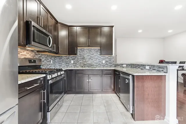 a kitchen with stainless steel appliances granite countertop a stove a sink and a microwave