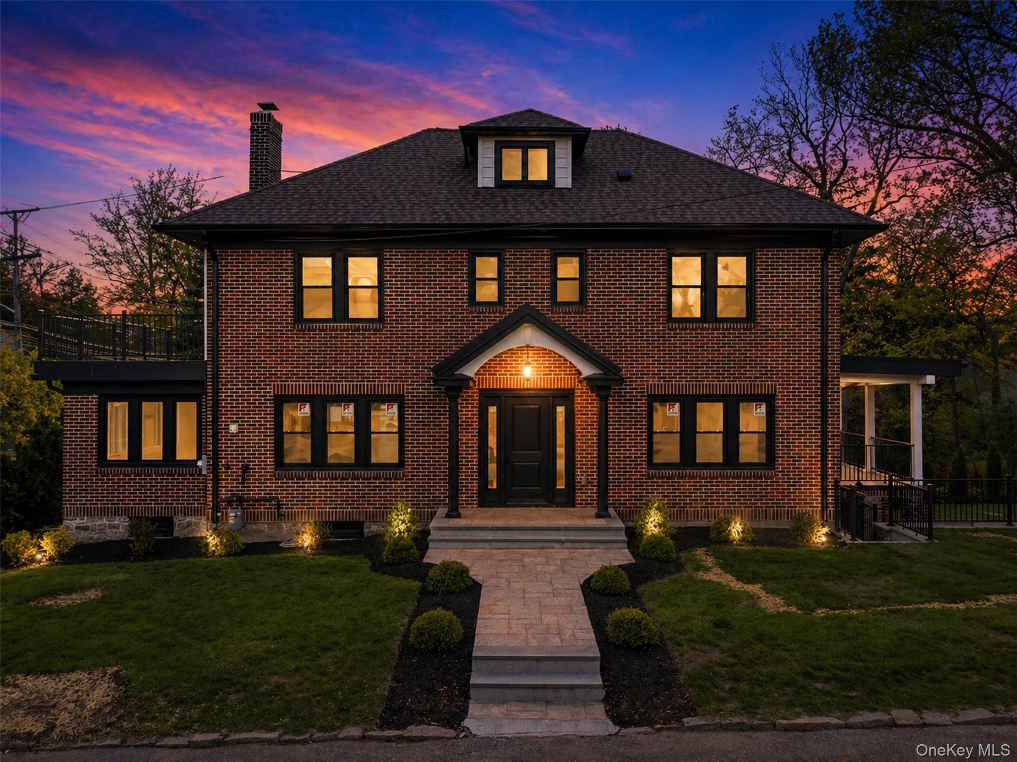 Brick exterior with black-framed windows, a covered front entry, and a stone walkway