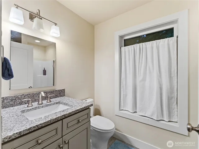 a bathroom with a granite countertop sink toilet and mirror