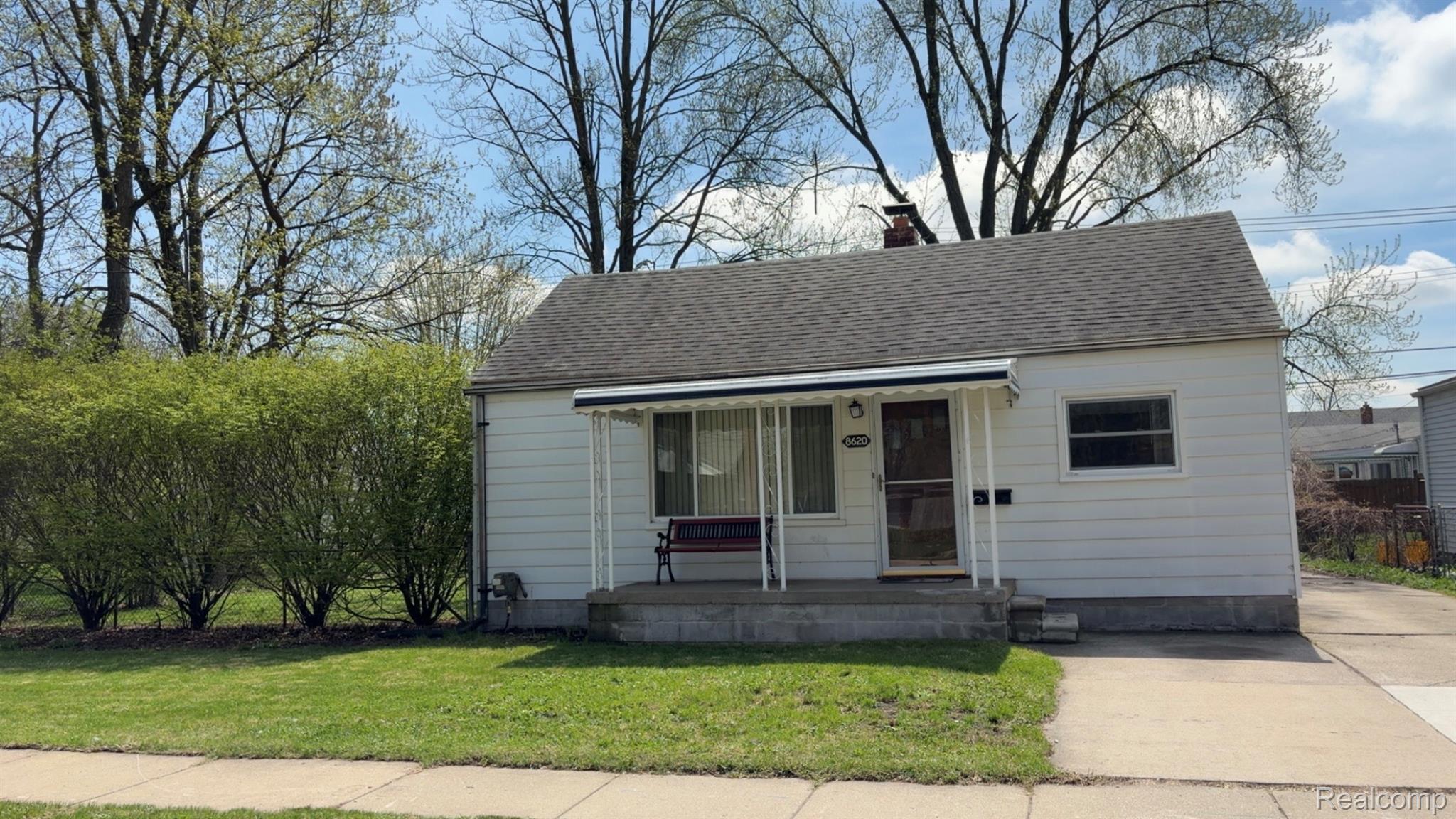 8620 Stephens Road Warren, MI 48089 - Photo 2 of 15 View of front of property featuring covered porch, a front yard, a shingled roof, and a chimney