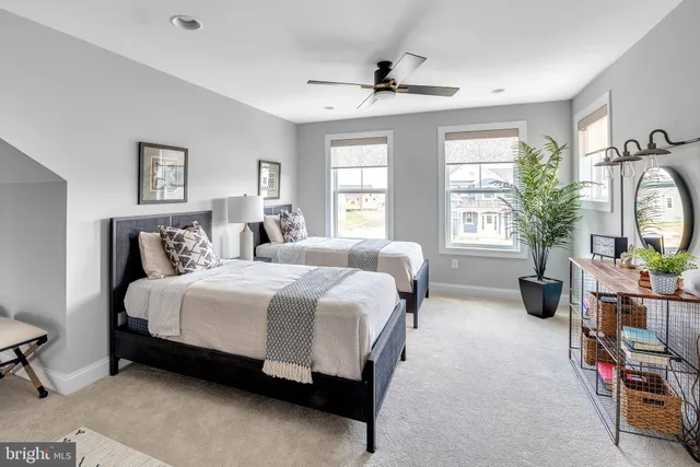 a spacious bedroom with a bed a large window and potted plant on the dresser