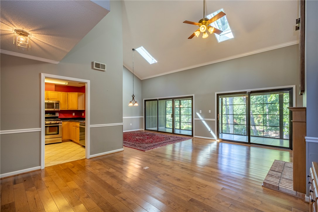 1302 Leeward Road Anderson, SC 29625 - Photo 8 of 50 A spacious living area with vaulted ceilings and large sliding glass doors opens to the surrounding greenery.