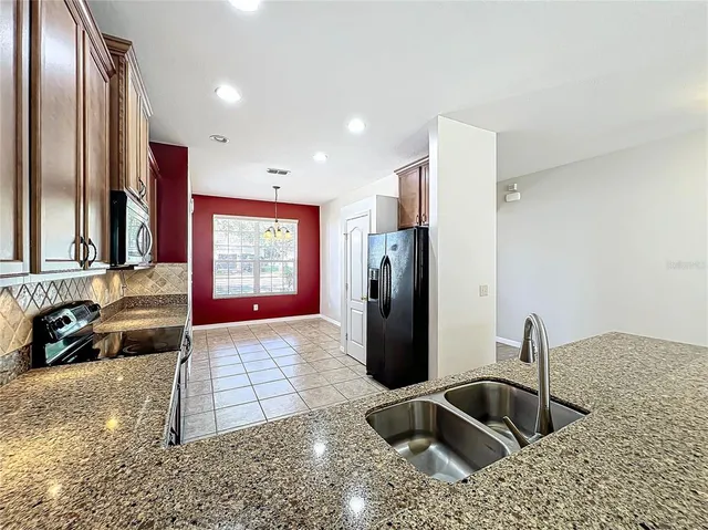 a kitchen with stainless steel appliances granite countertop a sink and a refrigerator