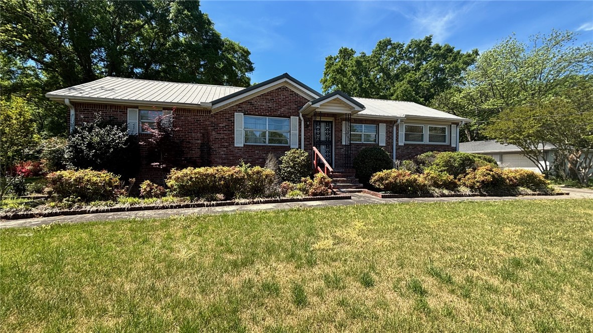 This classic brick residence features a durable metal roof and lush landscaping, creating inviting curb appeal.