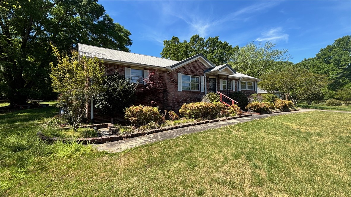 270 Flat Rock Road Liberty, SC 29657 - Photo 4 of 18 This classic brick residence features a durable metal roof and lush surrounding greenery.