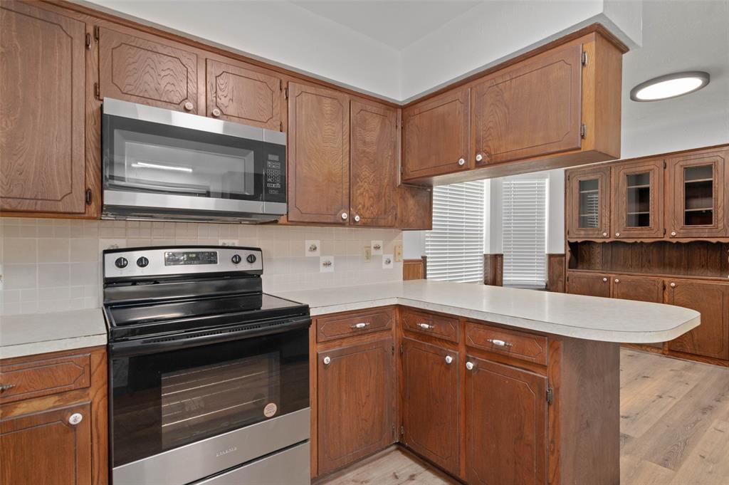 301 East 6th Street Krum, TX 76249 - Photo 3 of 29 Kitchen featuring wood cabinetry, solid surface countertops, a tile backsplash, and stainless steel appliances including a range and an over-the-range microwave