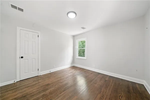 a view of an empty room with wooden floor and a window