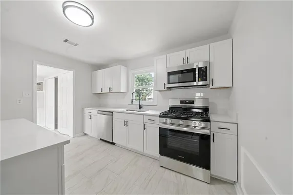 a kitchen with granite countertop white cabinets and stainless steel appliances