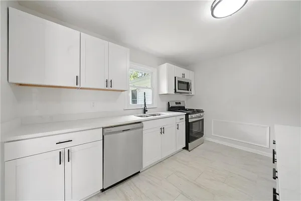 a kitchen with white cabinets appliances and a window