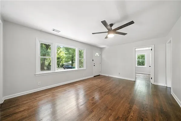 an empty room with wooden floor and windows