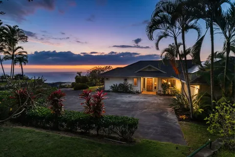 a front view of a house with a yard and mountain view in back