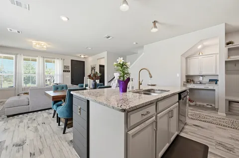 a kitchen with stainless steel appliances kitchen island granite countertop a kitchen island a stove a refrigerator a sink dishwasher a dining table and chairs with wooden floor