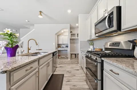 a kitchen with stainless steel appliances granite countertop a kitchen island hardwood floor sink stove dining table and chairs