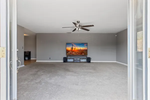 an empty room with windows and ceiling fan