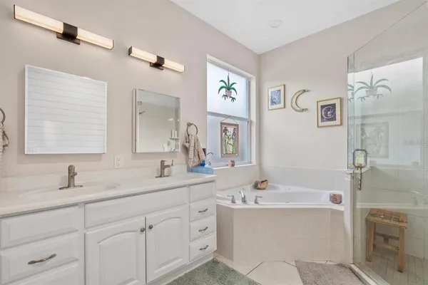 a bathroom with a tub sink double vanity and mirror