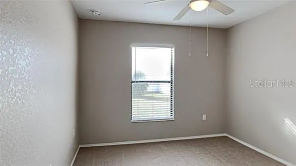 an empty room with a chandelier fan and windows