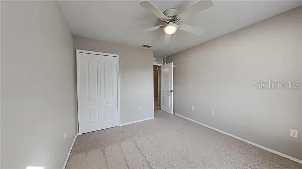 an empty room with a window and a ceiling fan
