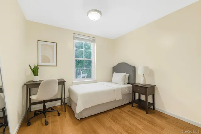 a bedroom with a bed table chair and a window