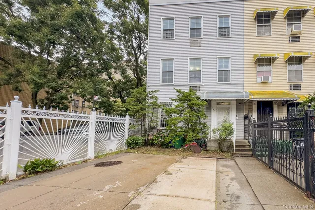 a view of a brick house with plants and wooden fence