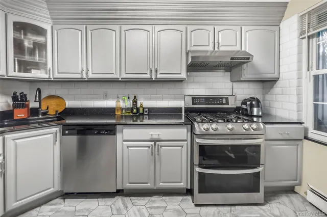 a kitchen with stainless steel appliances granite countertop white cabinets and a stove