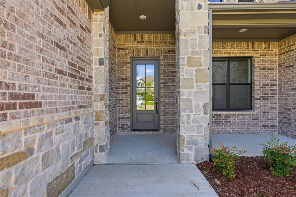 713 Anne Road Van Alstyne, TX 75495 - Photo 2 of 29 Covered entry featuring a paneled front door with glass inserts, flanked by brick and stone veneer